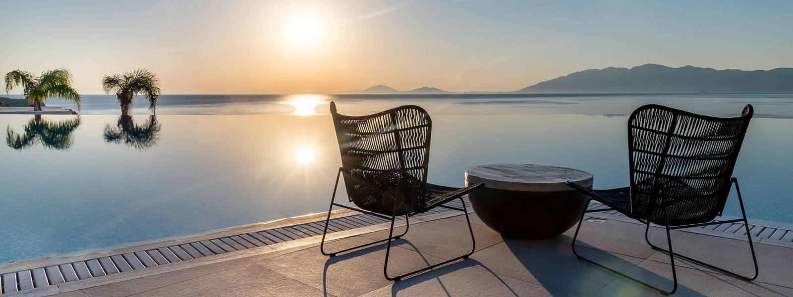 
Table with chairs in front of the pool at sunrise