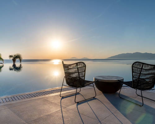 
Table with chairs in front of the pool at sunrise